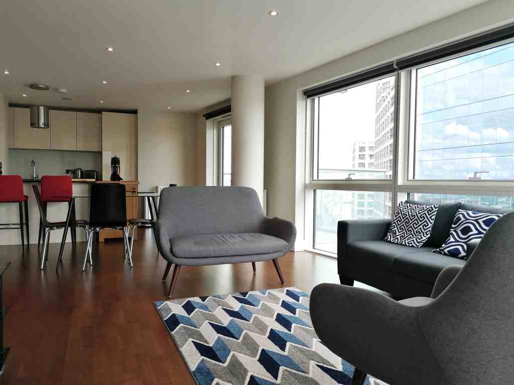 Bright living space with large windows offering city views, featuring stylish sofas and a contempora.