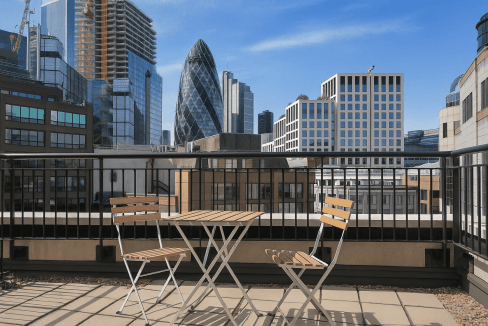 Panoramic view of London’s skyscrapers, including the Gherkin, from a balcony with outdoor furniture.
