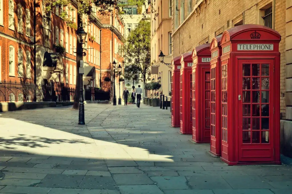 London street with iconic red telephone booths and charming architecture.