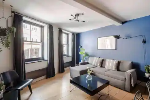 Spacious living area featuring a gray sofa, black coffee table, and vibrant blue accent wall.