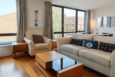 Spacious living room featuring a white sofa, armchair, and wooden coffee table with city views.