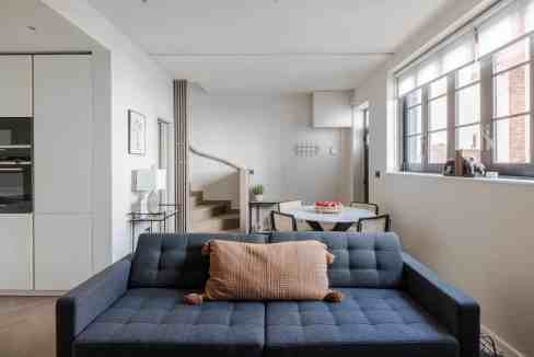 Contemporary living room featuring a navy sofa, cozy cushions, and large windows in Regent's Park Hu.