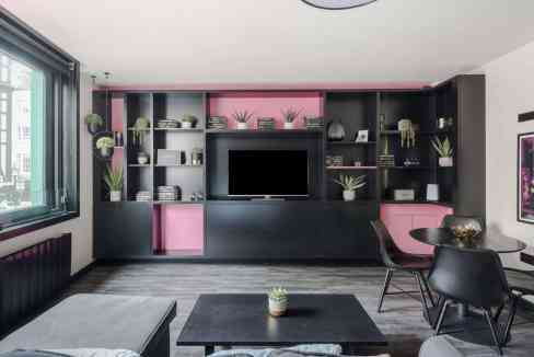 Stylish living room with black and pink shelving, potted plants, and contemporary furniture in Soho.