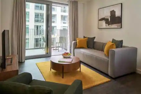 Bright living room with large glass doors opening to a balcony, featuring contemporary furniture and.