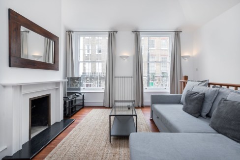 Bright living room with large windows and modern furnishings in Fitzroy Square Garden Apartments.