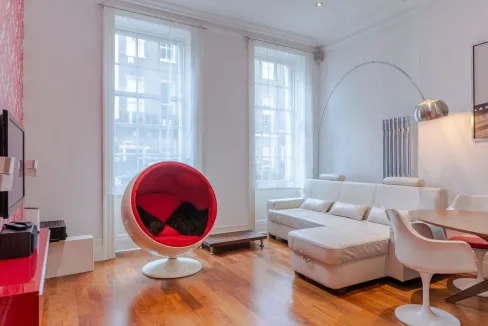 Modern living room with white sofa and unique red pod chair.