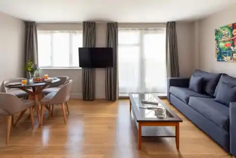 Spacious living room in Limehouse with a comfortable sofa, dining table, and large windows for natur.