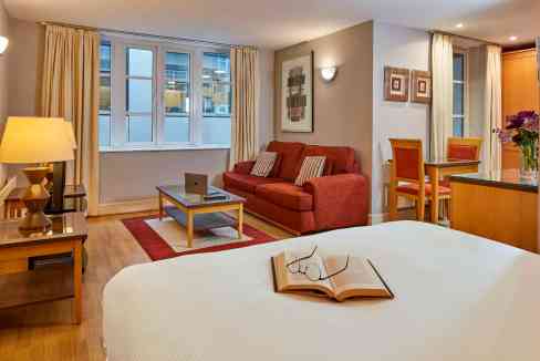 Spacious living room with large windows, cozy sofa, and elegant decor in Mansion House Queen Street.