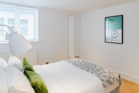 Bright bedroom in Fulham Road Apartments featuring a clean design, white walls, and contemporary fur.