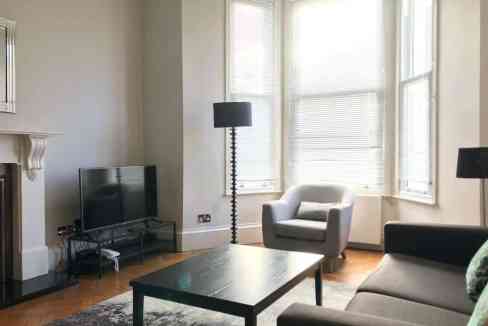 Bright living room with large windows, comfortable armchair, and contemporary furniture.