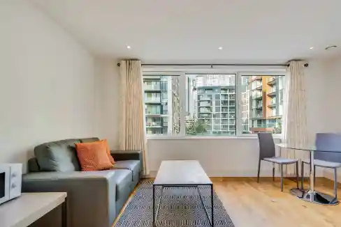 Modern living room with large windows, sofa, and dining area in Indescon Square Serviced Apartments.