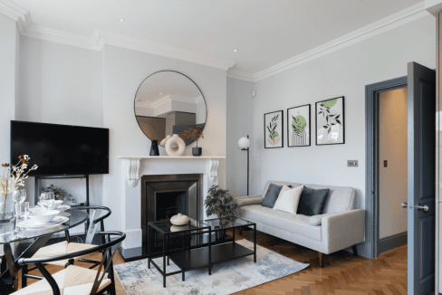 Stylish living room with sofa, fireplace, and wall art at Margravine Gardens Apartments.