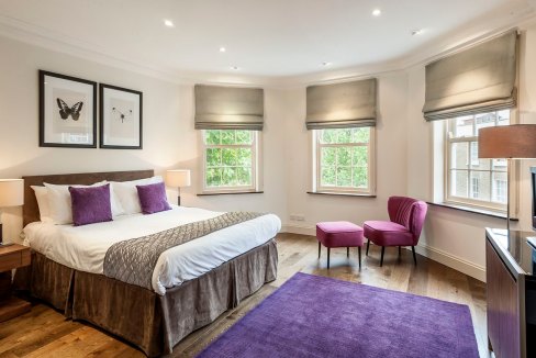 Bright bedroom featuring large windows, purple accents, and contemporary furniture. Perfect for comf.