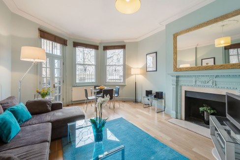 Bright living room with large windows, elegant fireplace, and modern furnishings. Perfect for comfor.