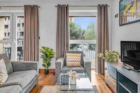 Bright living room in Hoxton Hackney Road apartment with large windows and stylish decor.