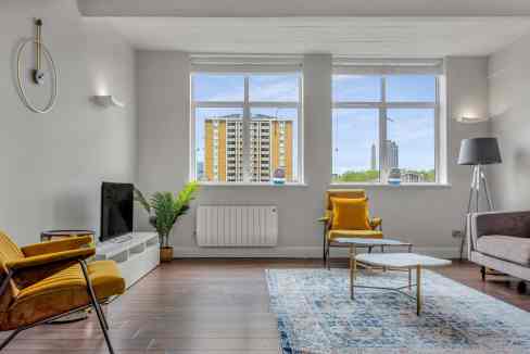 Bright urban living room with large windows overlooking city skyscrapers and modern decor.
