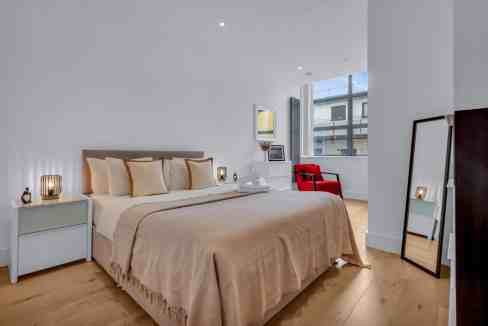 Spacious bedroom with a large bed, stylish decor, and natural light at Regent's Park Serviced Apartm.