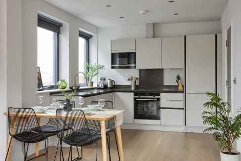 Bright, contemporary kitchen featuring white cabinetry, black countertops, and large windows at Harr.