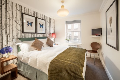 Cozy bedroom with stylish decor, butterfly artwork, and natural light in Marylebone Chiltern Street.
