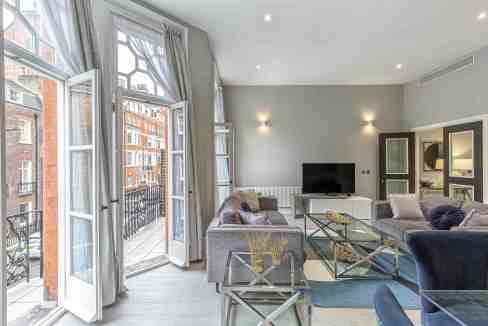 Bright living room with large windows and elegant furnishings at Mayfair Green Street Apartments.