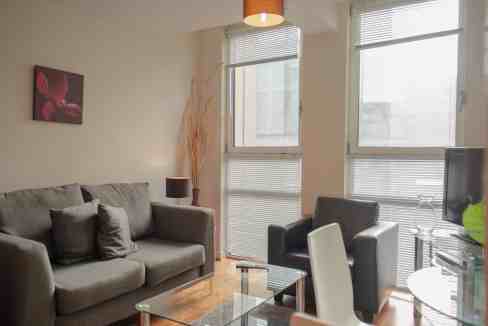 Bright living room with large windows and contemporary furniture in Barbican Lamb's Passage Apartmen.