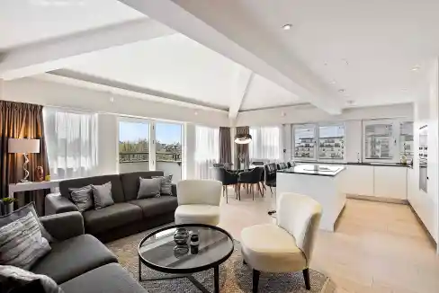 Spacious living room with modern furniture and large windows overlooking the cityscape.