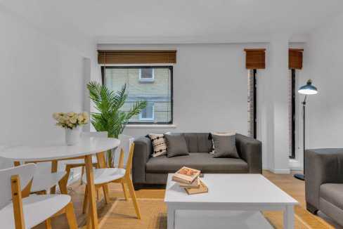 Bright living room with sofa, dining area, and large windows in a contemporary home.