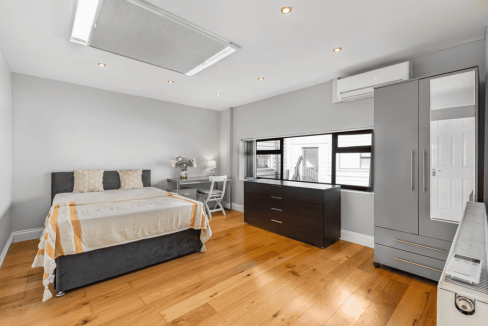 Apartment bedroom with minimalist decor, large windows, and wooden flooring in Holloway Camden Road.