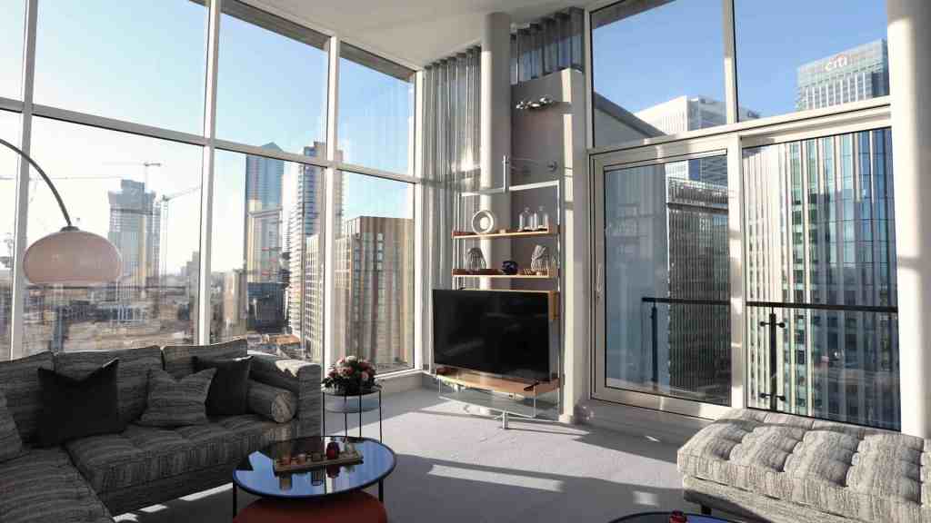 Bright living room with floor-to-ceiling windows overlooking Canary Wharf skyline.