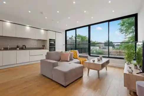 Bright living room with large windows and contemporary furniture in Dalston apartment.