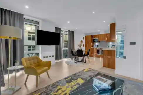 Bright living room with large windows, contemporary furniture, and a flat-screen TV.