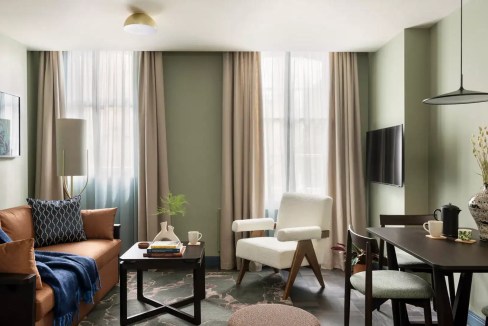 Bright living room with large windows and modern furniture in Kensington Cromwell Road Apartments.