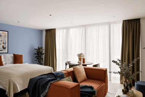Modern living room with large windows, cozy sofa, and stylish decor in Canary Wharf luxury apartment.