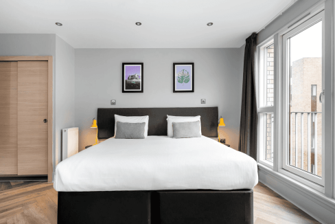 Comfortable double bed with white linens and cozy pillows in a bright, stylish room.