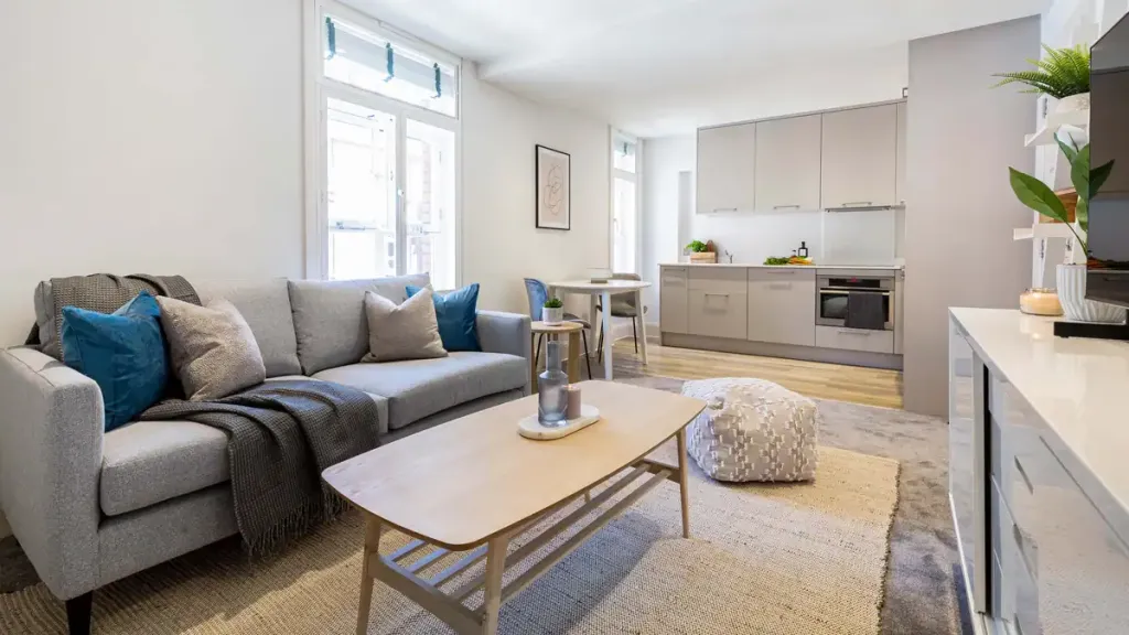 Bright and airy living room with sofa, cushions, and natural light in Bond Street apartments.