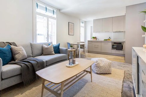 Bright and airy living room with sofa, cushions, and natural light in Bond Street apartments.