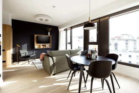Spacious living area with black accent wall, flat-screen TV, and natural light.