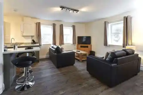 Living room in Swindon High Street Apartments with cozy seating and bright windows.