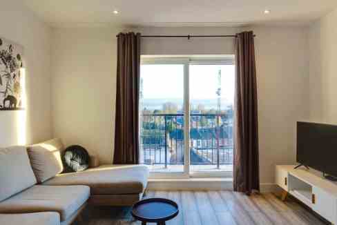 Bright living room with large window and balcony view.