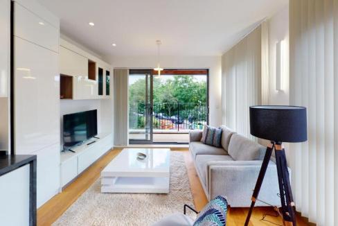 Bright living room with large windows and sliding glass door at Kew Bridge Gardens Apartments.