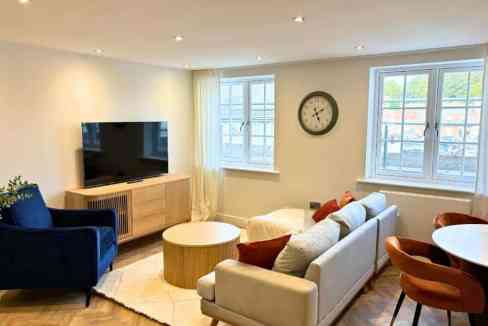 Bright living room in Salisbury Centre Apartments with cozy sofas and a flat-screen TV.