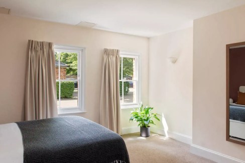 Interior view of a bright, cozy bedroom at Reading Castle Crescent Apartments with large windows and.