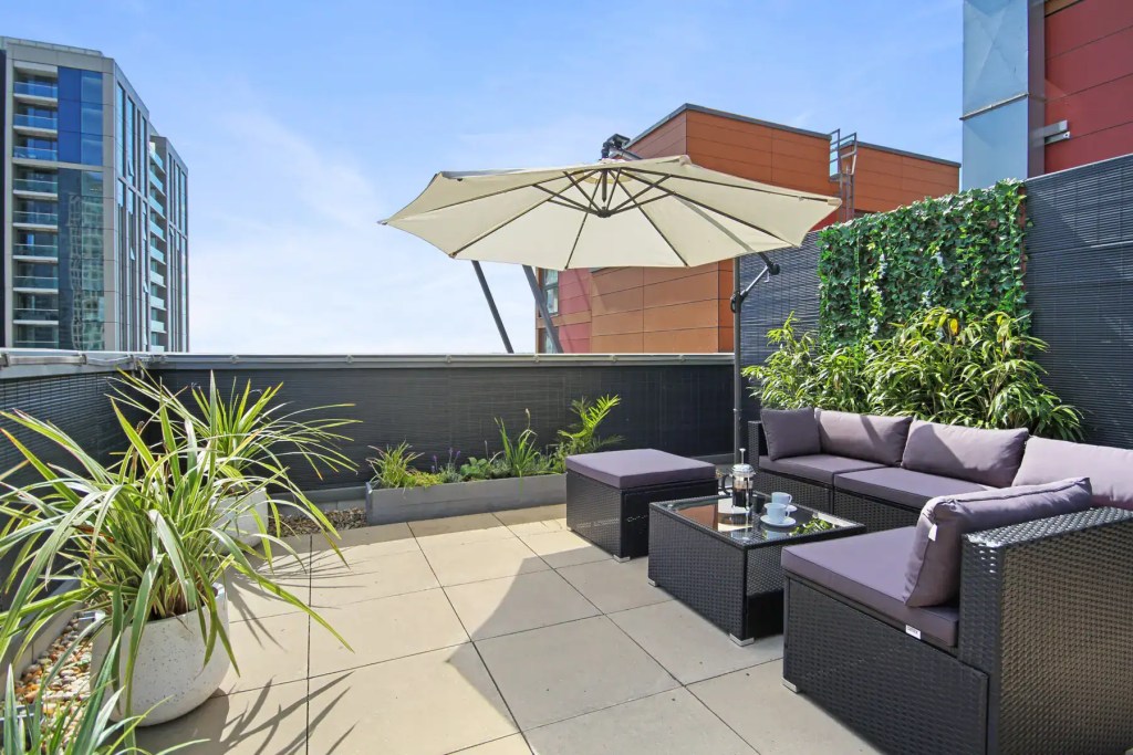 Rooftop terrace with outdoor seating and umbrella at South Quays Serviced Apartments.