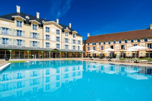 Outdoor swimming pool at Disneyland Paris Aparthotel with modern hotel buildings in the background.