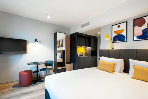 Comfortable hotel room at Frankfurt Airport Aparthotel featuring contemporary design and vibrant art.