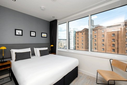 Bright hotel room at Manchester Piccadilly Station Aparthotel with large windows overlooking histori.