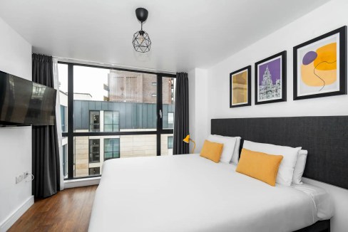 Bright hotel room with stylish furnishings, artwork, and city views in Liverpool.