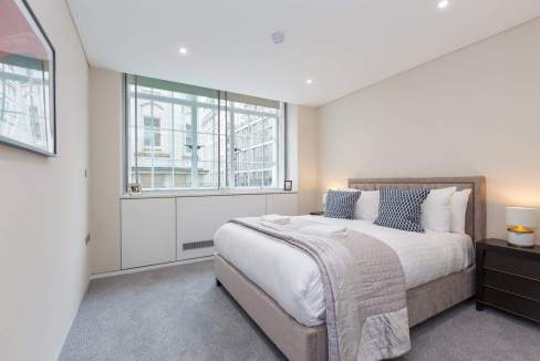 Bright bedroom with large window overlooking city buildings in Covent Garden Exeter Street.