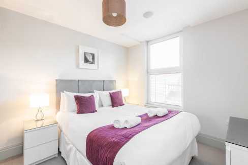 Modern bedroom in Richmond apartments with white walls and purple accents.