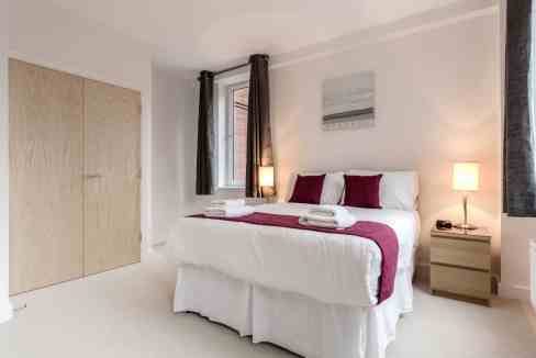 Modern bedroom in Sutton Serviced Apartments with cozy bedding and natural light.